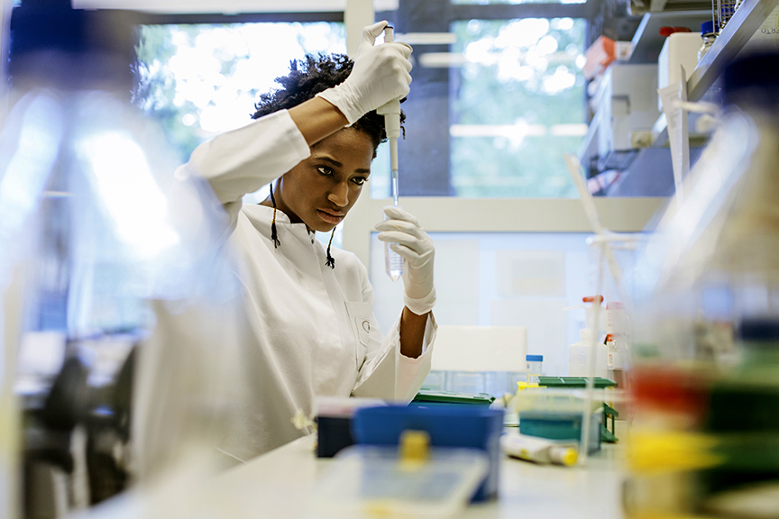 A scientist in a lab coat looking at a test tube