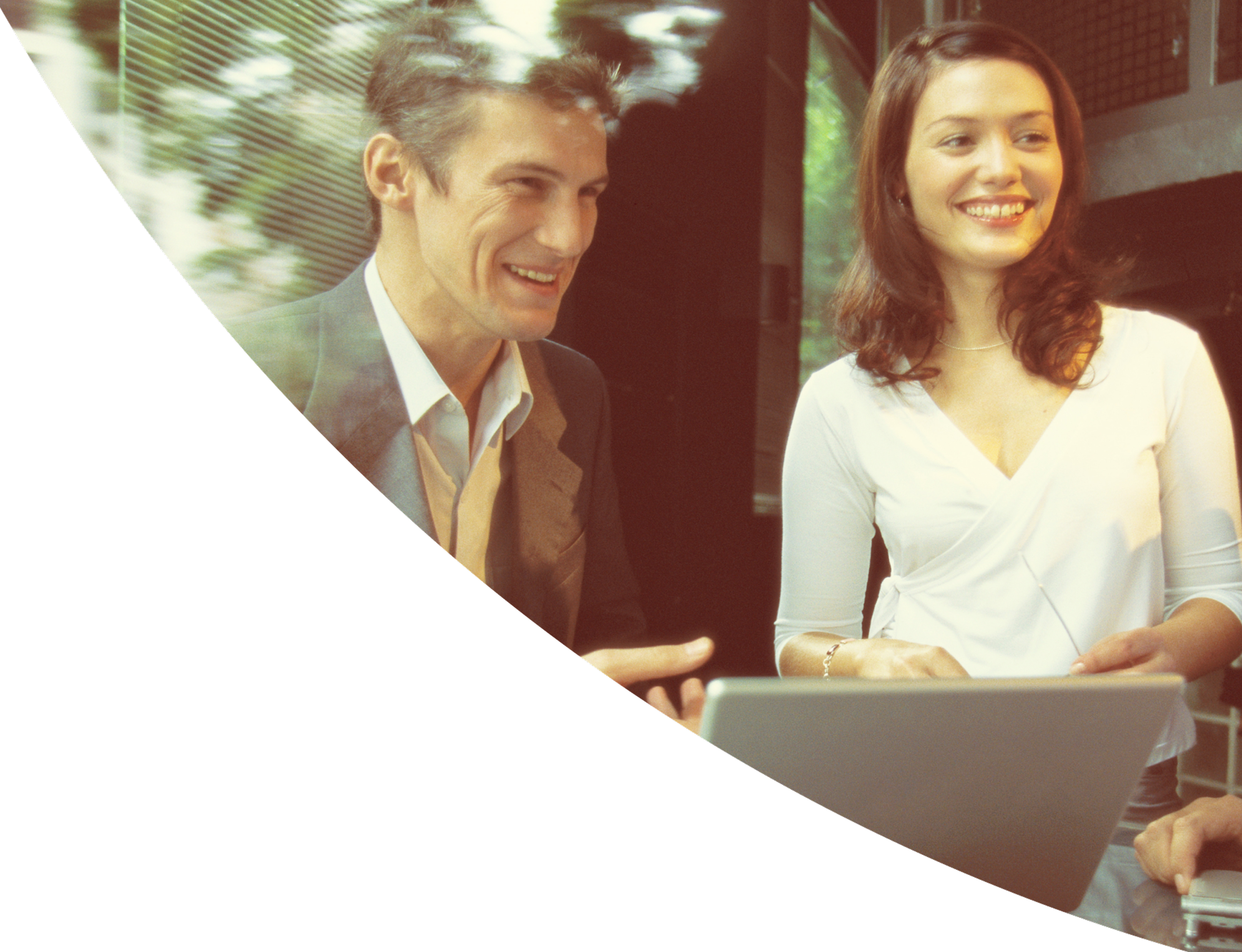 Two colleagues smiling while working on a laptop