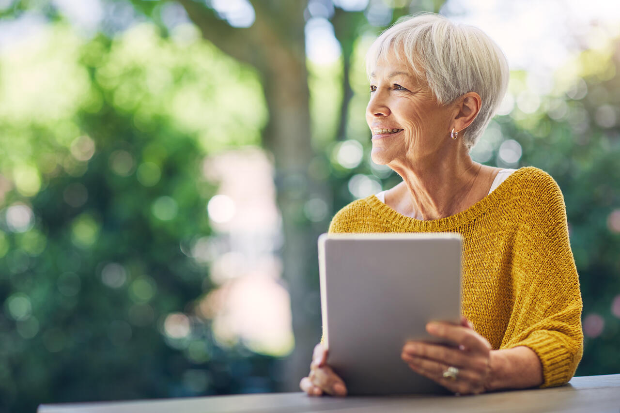 A lady smiling whilst using a tablet