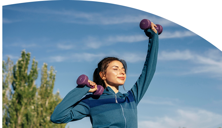 Woman stretching outdoors with hand weights