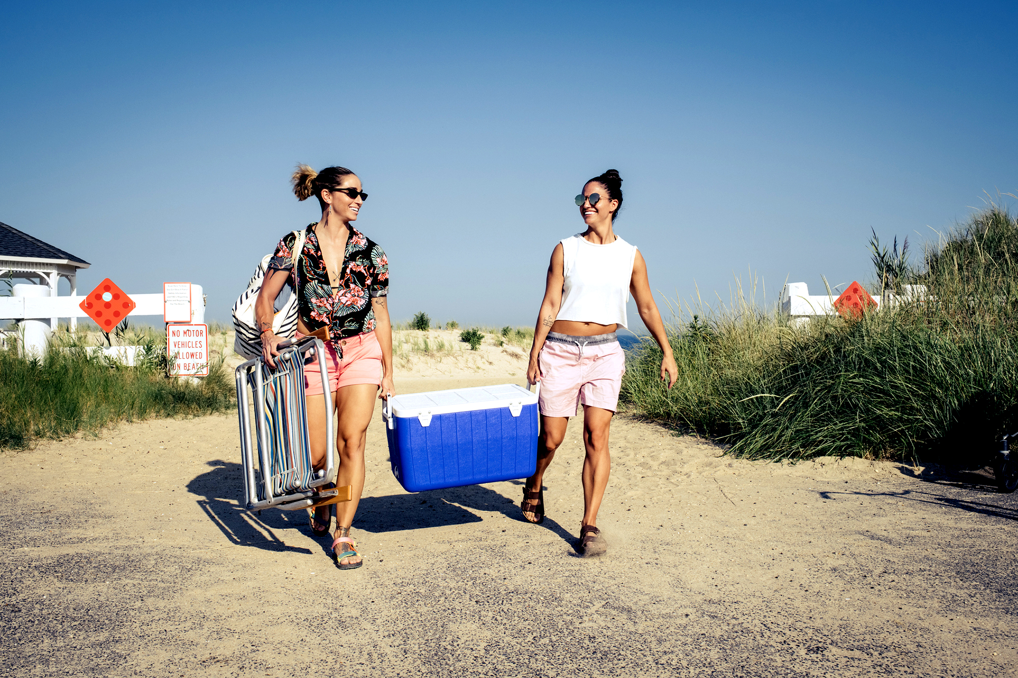 2 people carrying a coolbox on a beach