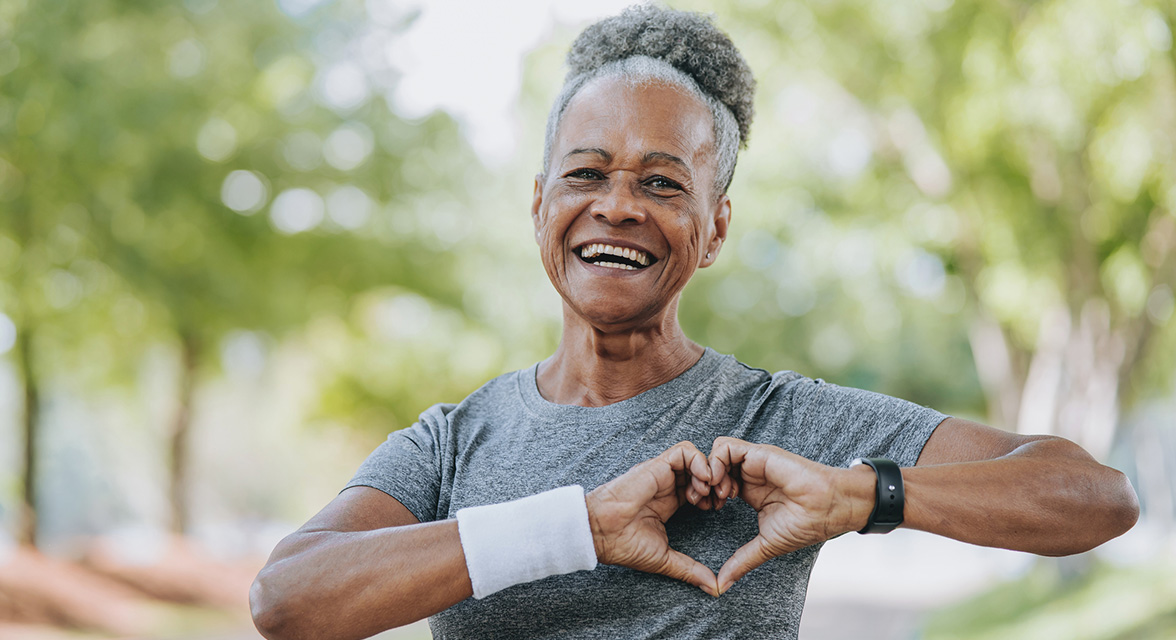An older woman with her hands in the shape of a heart