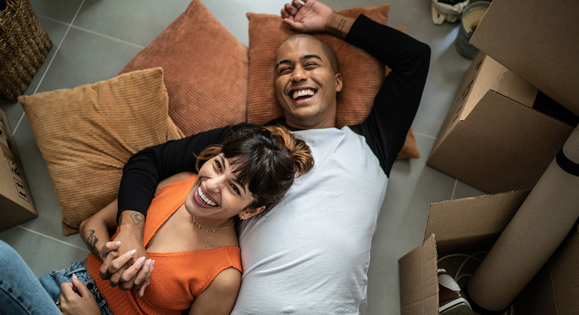 A man and a woman laughing on a sofa